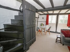 A staircase leading to a dining area with a table and chairs, a grey sofa, and a red curtain.