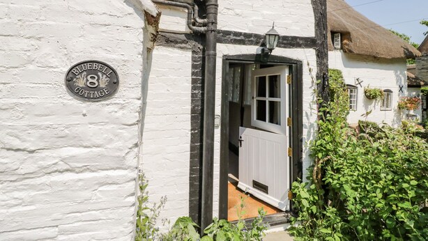 A traditional white cottage with a black door, a visible window, and a sign indicating it is number 8. - Bluebell Cottage (Stratford-upon-Avon)