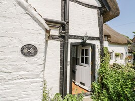 A traditional white cottage with a black door, a visible window, and a sign indicating it is number 8.