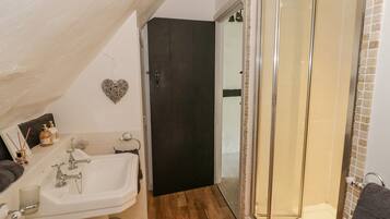 A bathroom with a white sink, a glass shower enclosure, and a dark door.