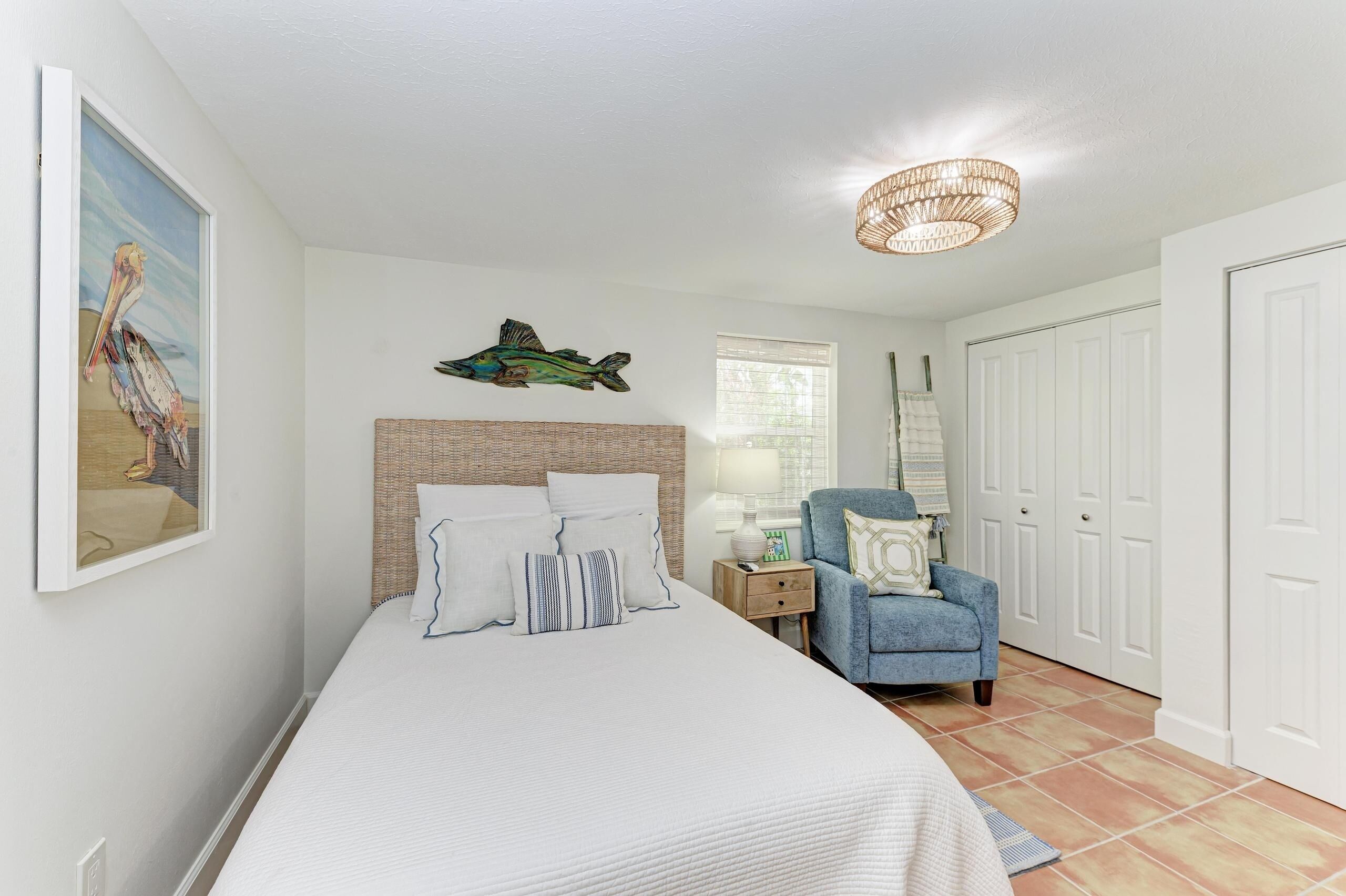 A bedroom with a bed, a nightstand, a chair, a lamp, and a wardrobe.