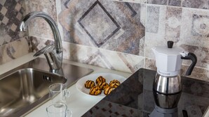 A kitchen with a stainless steel sink, a coffee maker, a plate of cookies, and two glasses. - Duomo Charme Studio by Wonderful Italy (Naples)