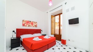 A hotel room with a red bed, a flat-screen TV, a painting on the wall, and a patterned floor. - Sorrento Hearts in Sorrento (Sorrento)