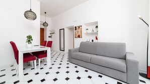A modern living room with a grey sofa, a dining table with red chairs, and a geometric patterned floor. - Sorrento Hearts in Sorrento (Sorrento)