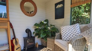 A cozy room with a fireplace, wicker furniture, a guitar, and a mirror on the wall. - Hangmans Cottage (Horncastle)