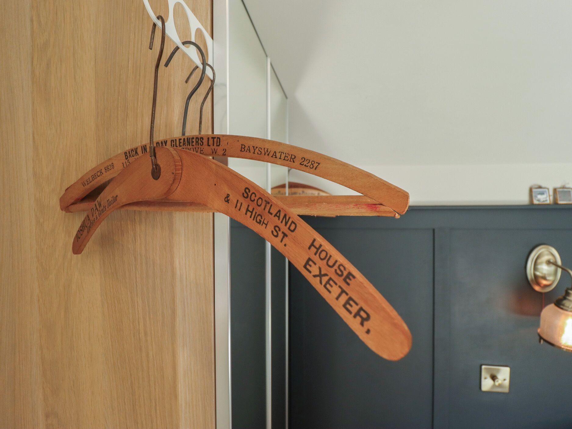 A wooden coat rack with hanging items, a dark door, and a light-colored wall.
