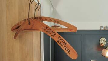 A wooden coat rack with hanging items, a dark door, and a light-colored wall.