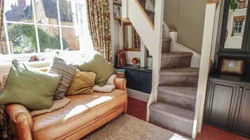 A living room with a leather sofa, a staircase, and a view of the outside.