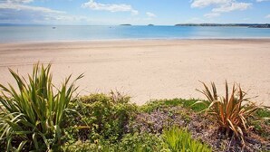 A beach with clear skies and calm waters. - E19 The Warren (Pwllheli)