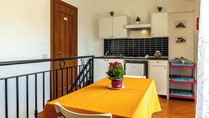 A kitchen with a dining table, cabinets, and a staircase. - Villetta Mari e Amuri (Giardini Naxos)