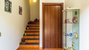 A staircase with a wooden door and a glass display case with decorative items. - Villetta Mari e Amuri (Giardini Naxos)