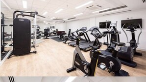 Une salle de sport équipée de machines de cardio, de matériel de musculation et dotée d’un mur entièrement recouvert de miroirs.
