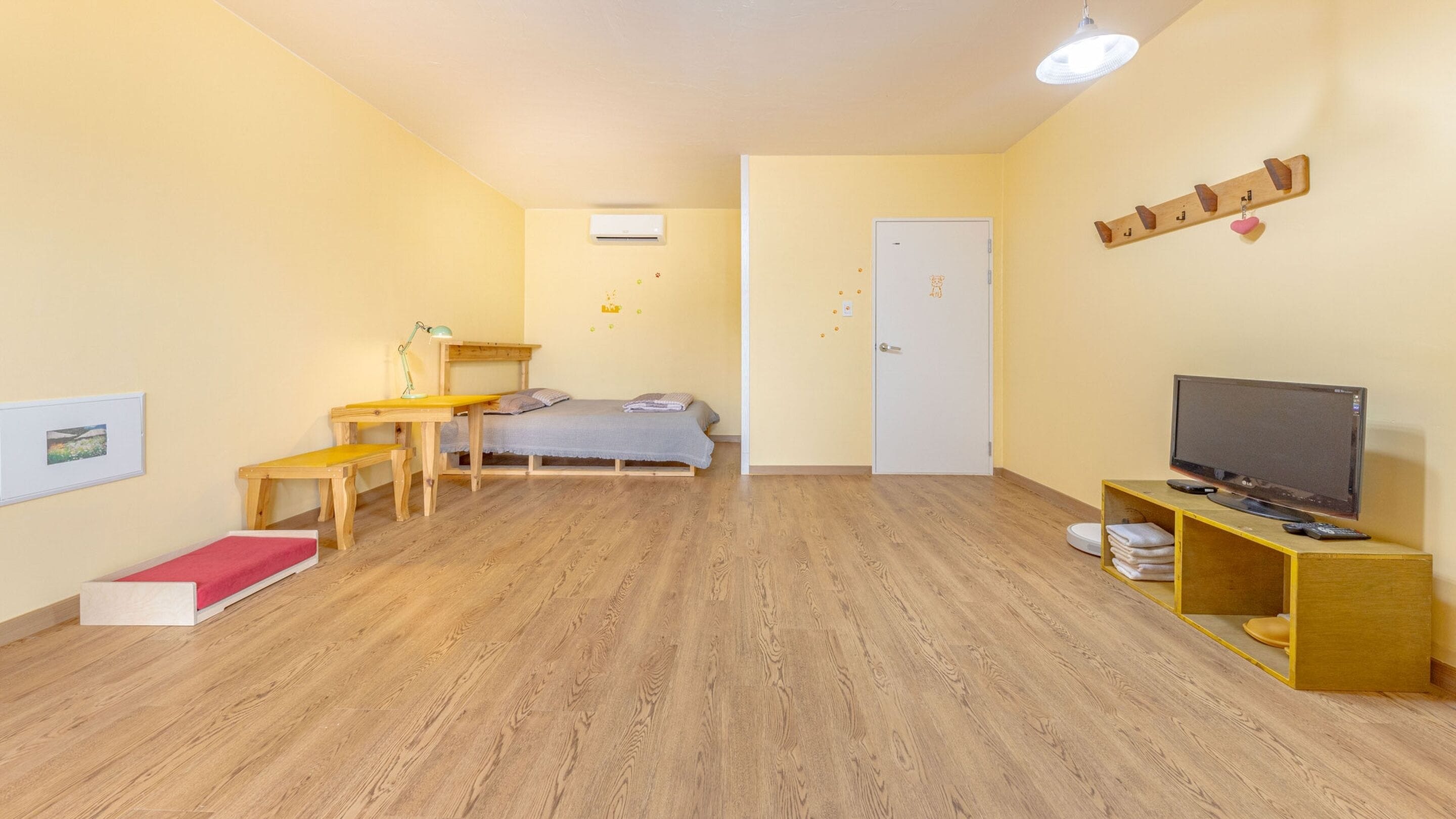 A room with a bed, a desk, a chair, a television, and a shelf with towels.