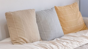Three pillows on a bed with a plain wall in the background.