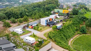 A residential area with modern houses, a white RV, and a green field.