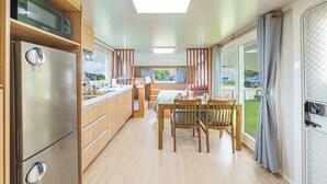 A compact kitchen with a built-in microwave, a refrigerator, and a dining area with a table and chairs. - Ganghwado Labyrinthos Companimal Pension (Incheon)