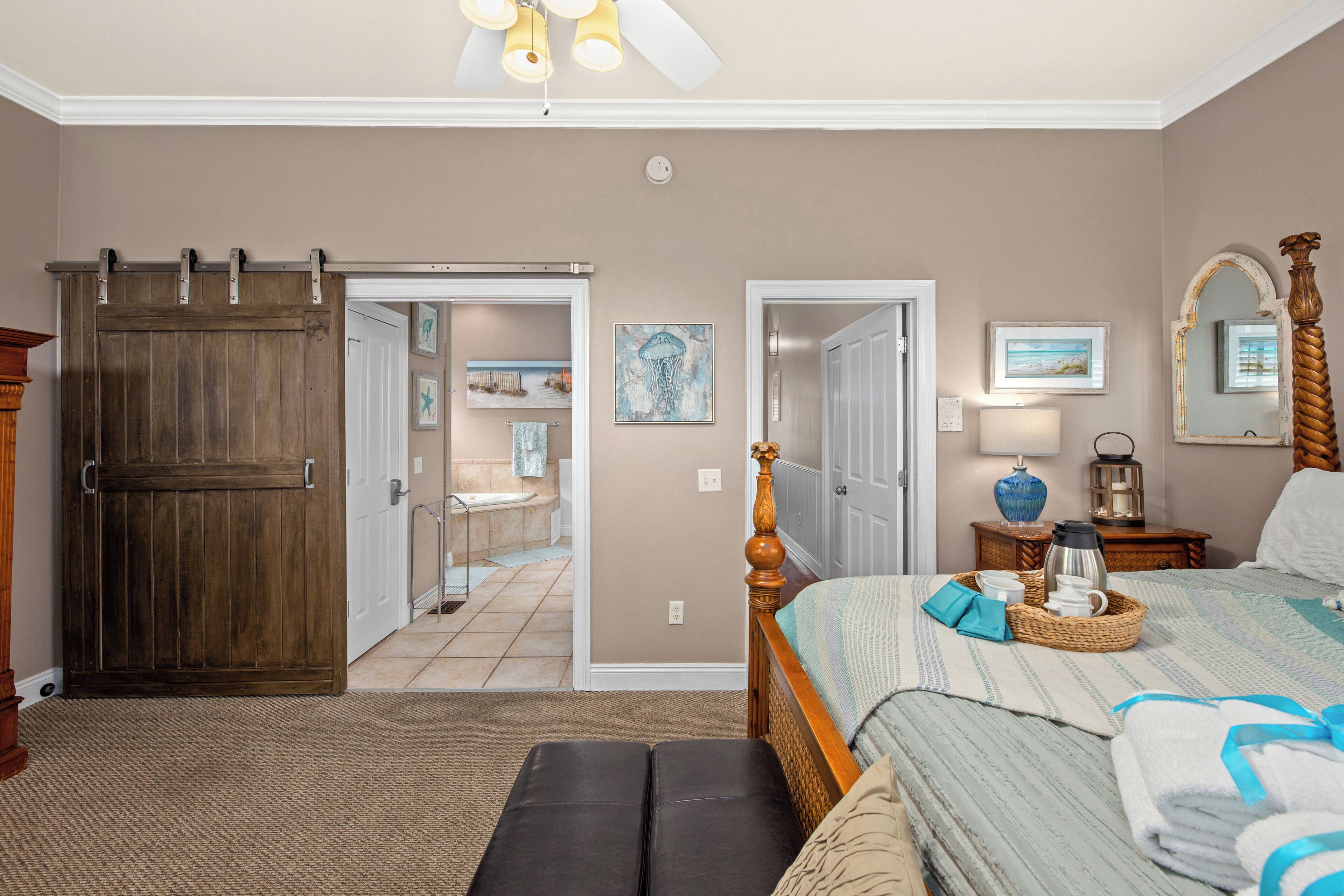 A bedroom with a large bed, a wooden wardrobe, a sliding door, and a bathroom visible through an open door.