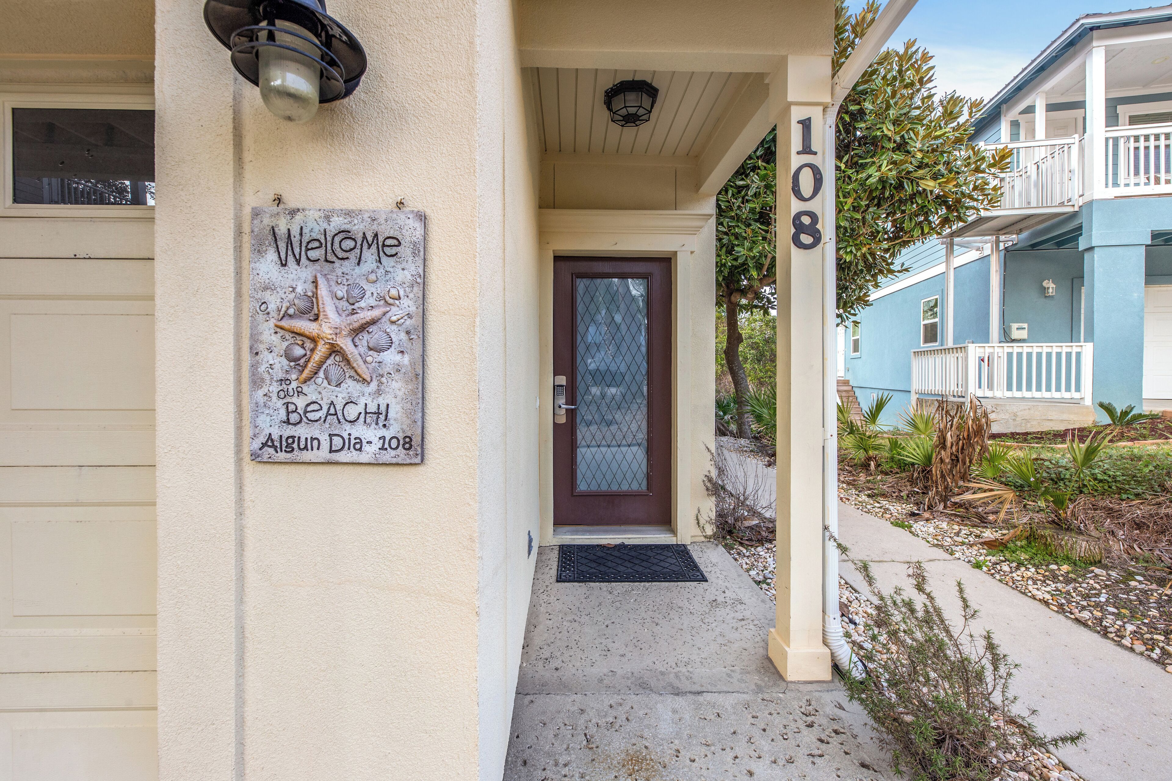 A house with a 'Welcome' sign, a brown door, and a number '108' on the wall.