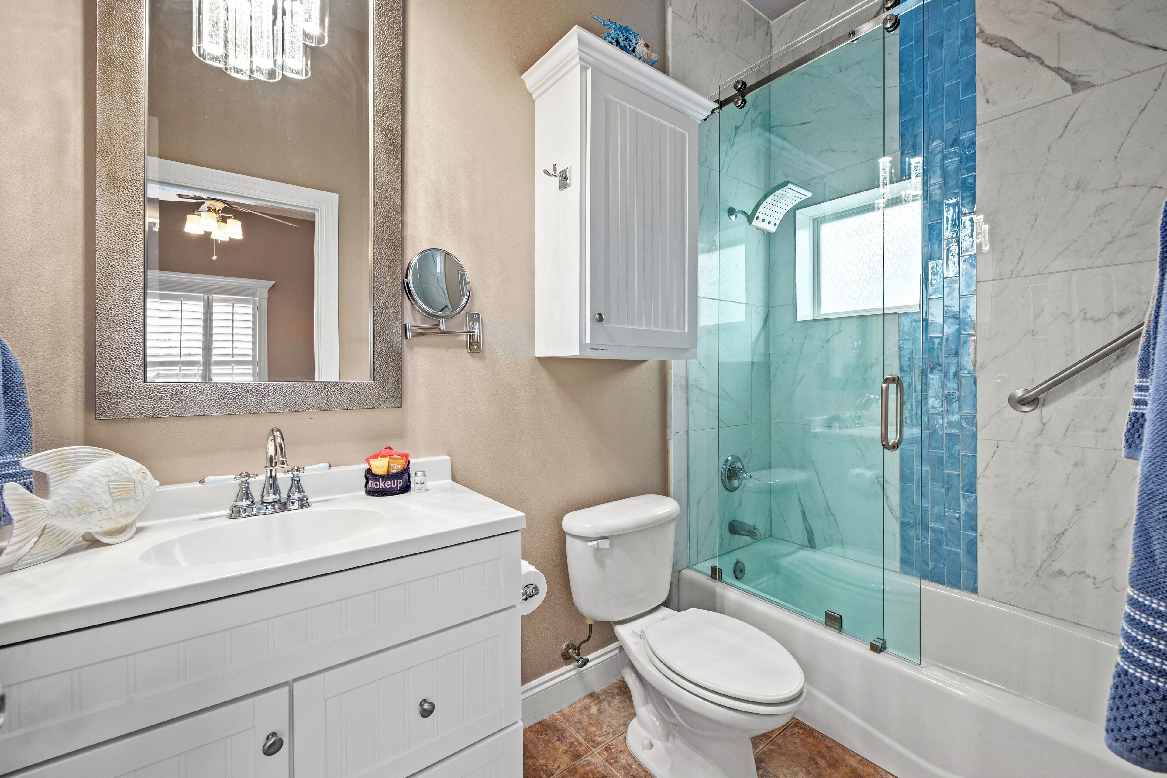A bathroom with a white vanity, a glass-enclosed shower, a toilet, and a large mirror.