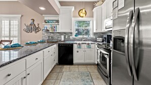 A modern kitchen with white cabinets, a stainless steel refrigerator, and a window above the sink. - Algun Dia - Plush Family-friendly Home - A Block From Beach (Panama City Beach)