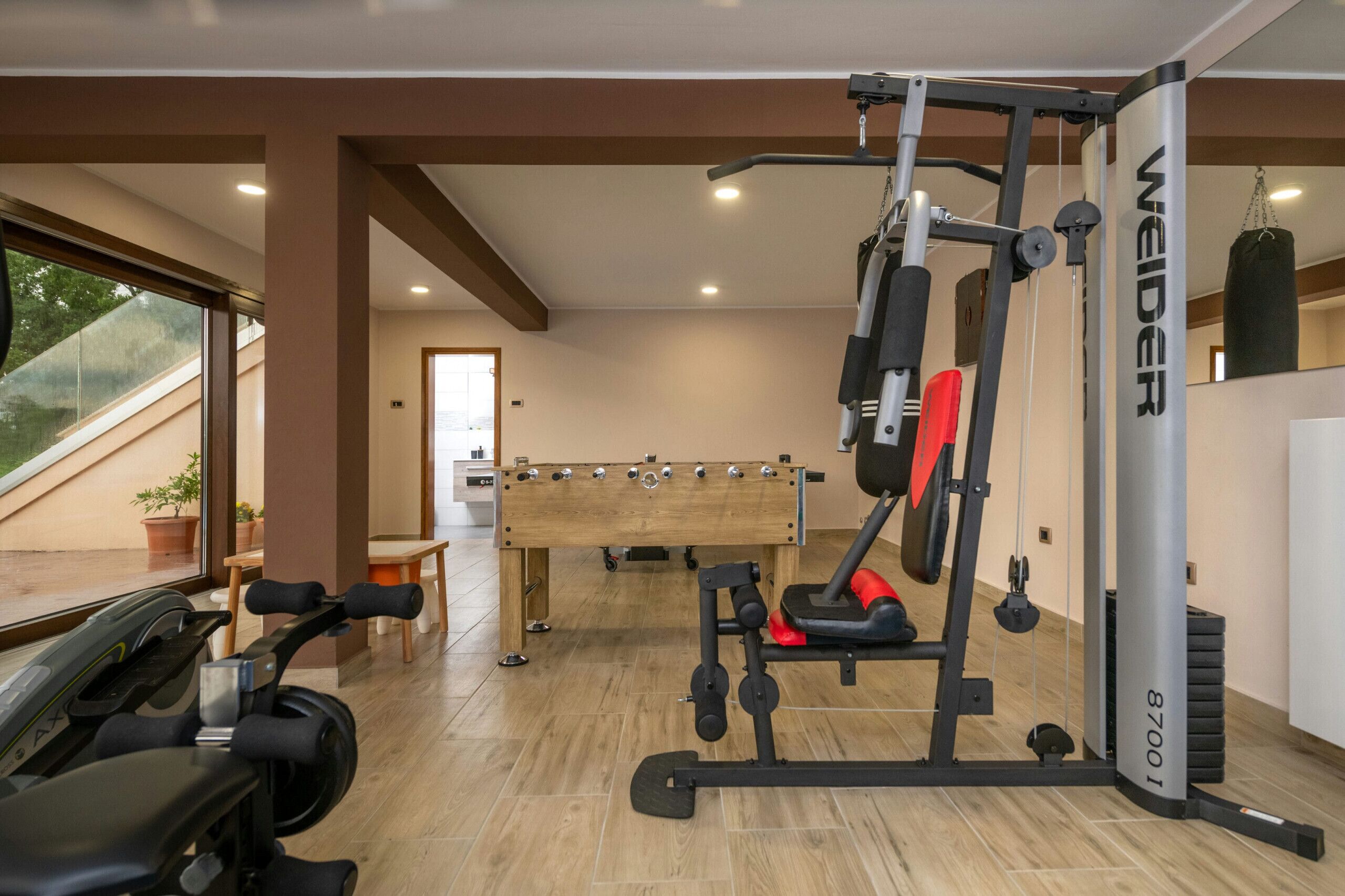 A gym with exercise equipment, a pool table, and a view of the outdoors.