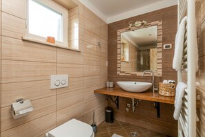 Ein modernes Badezimmer mit einem Holzlager, einem großen Spiegel und einem weißen Waschbecken.
