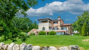 A modern two-story house with a stone facade, large windows, and a well-maintained lawn. - Villa Casa Brazzana (Buzet)