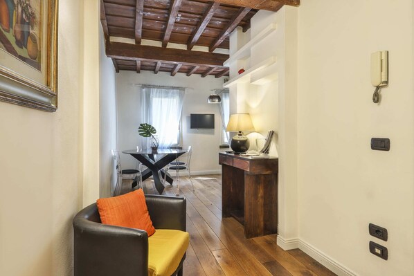 Une pièce avec un plafond en bois, un coin repas avec une table et des chaises, une lampe et un téléphone fixé au mur.