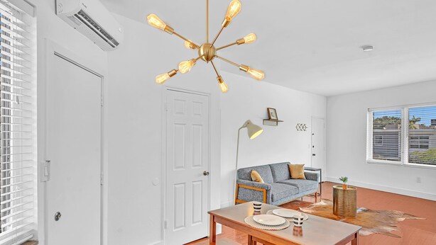A modern living room with a wooden dining table, a sofa, and a unique ceiling light fixture. - Garden Suite 3-hosted by Sweetstay (Miami Beach)
