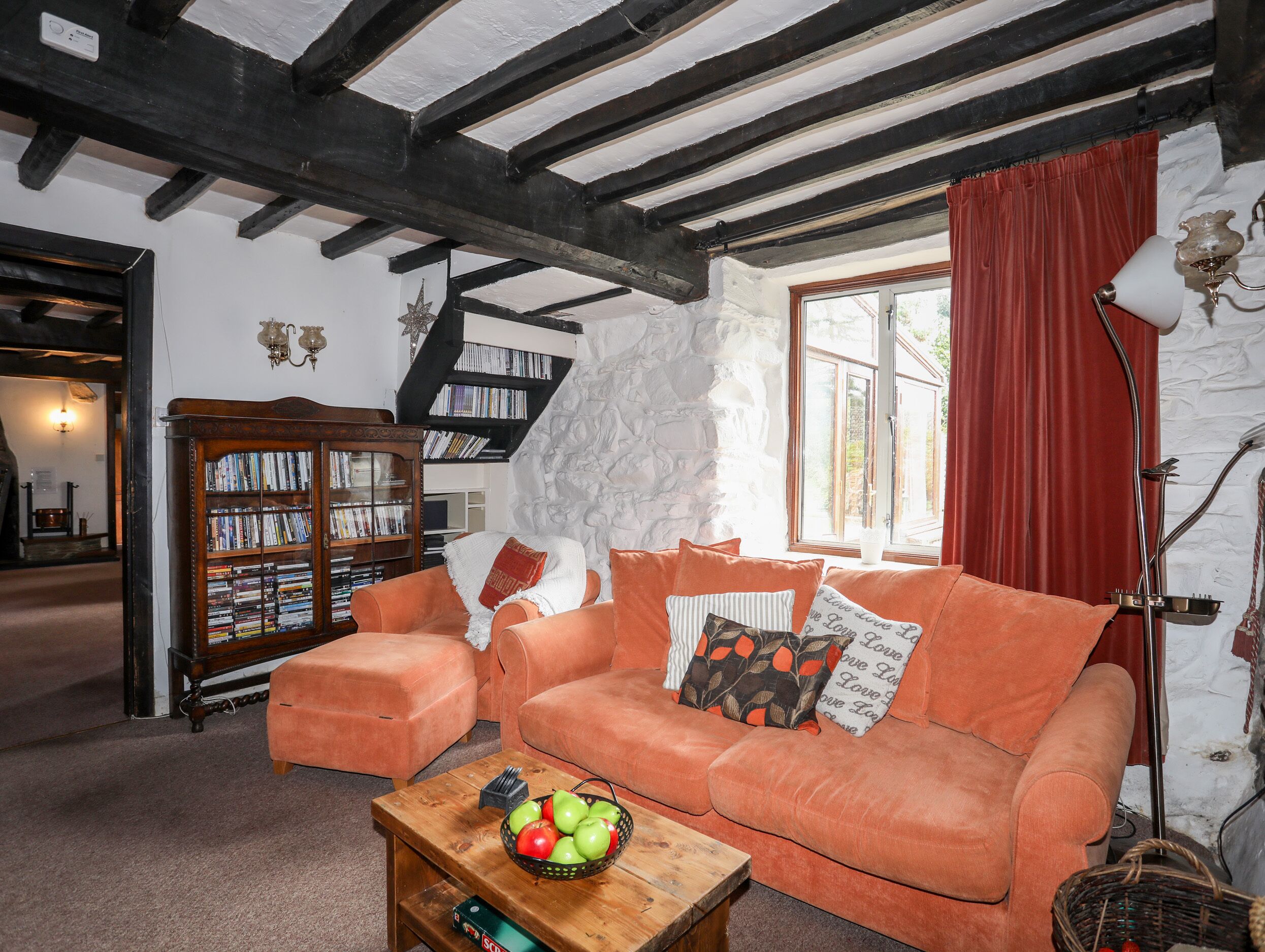 A cozy living room with a wooden coffee table, a sofa, and a bookshelf.