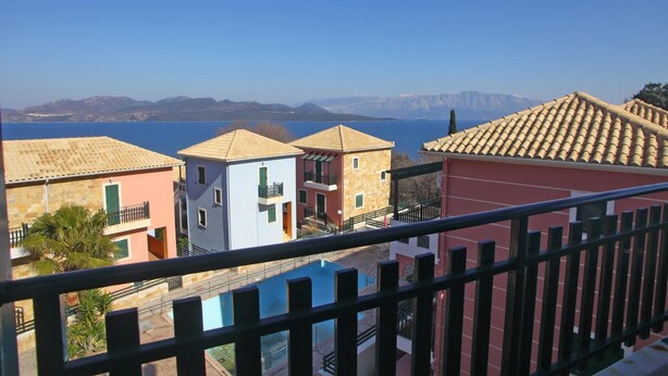 A coastal residential area with buildings overlooking a body of water and mountains. - Charming 4-bed House in Nikiana (Lefkada)