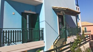 A two-story building with a balcony, a staircase, and a small garden area. - Charming 4-bed House in Nikiana (Lefkada)
