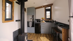 A compact kitchen with a wood stove, built-in oven, and a sink. - 1 Bed Hut - Sleeps 4 - Pets - Parking (Minehead)