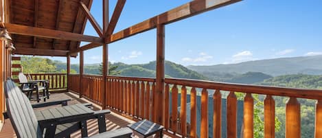 Eine Holzterrasse mit Sitzgelegenheiten und Blick auf eine Berglandschaft.