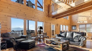 A spacious wooden interior with two leather sofas, a coffee table, and a rug. - Theatre in the Mountains by Jackson Mountain Rentals (Sevierville)