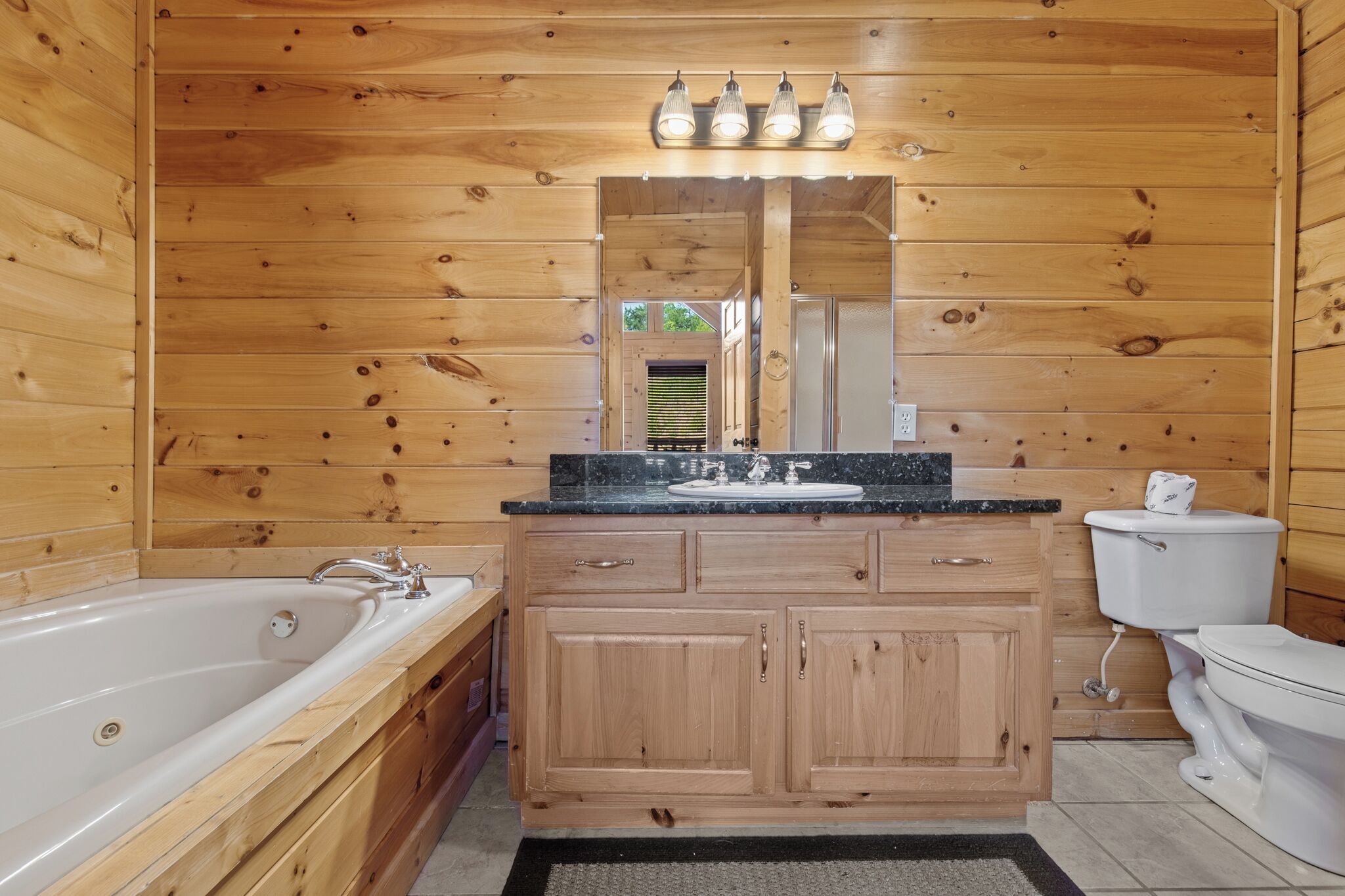 A wooden cabin bathroom with a bathtub, vanity, and toilet.
