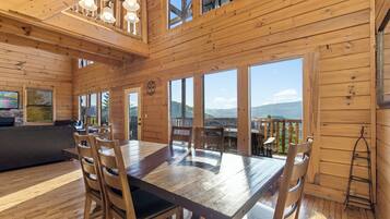 A wooden interior with a dining table, chairs, and a sofa.
