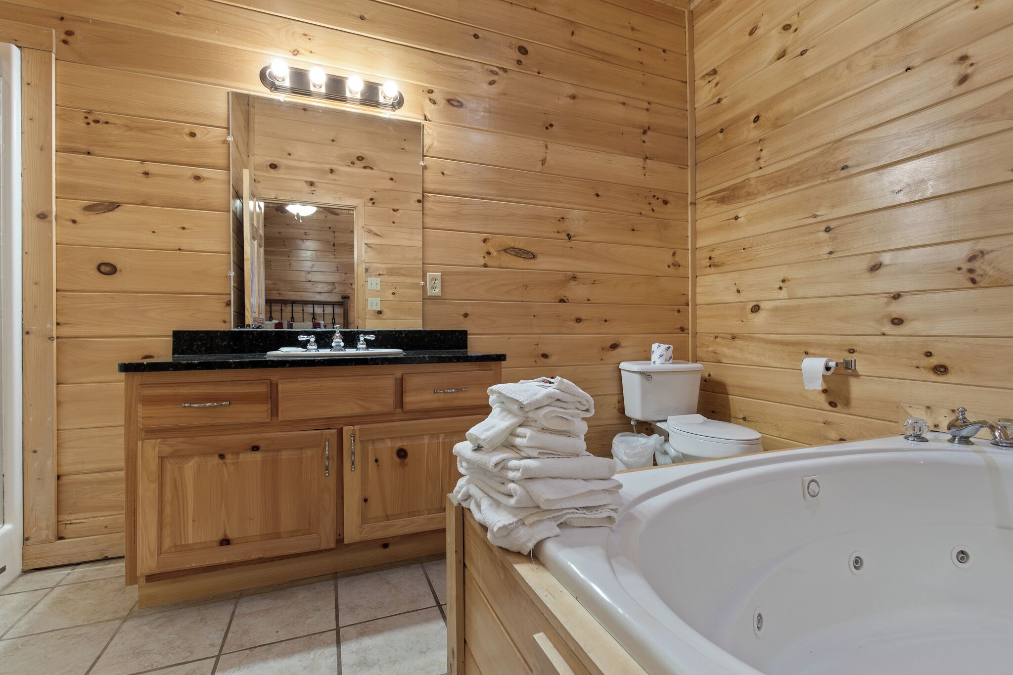 Un baño con paneles de madera, un lavabo, espejo, inodoro y bañera.