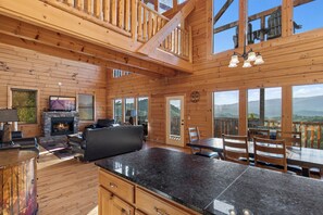 A spacious wooden cabin with a fireplace, a dining area, and large windows offering mountain views. - Theatre in the Mountains by Jackson Mountain Rentals (Sevierville)