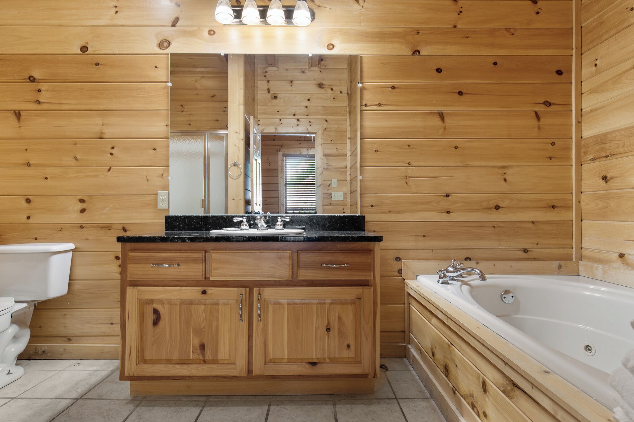 Baño de cabaña de madera con lavabo, tocador, inodoro y bañera.