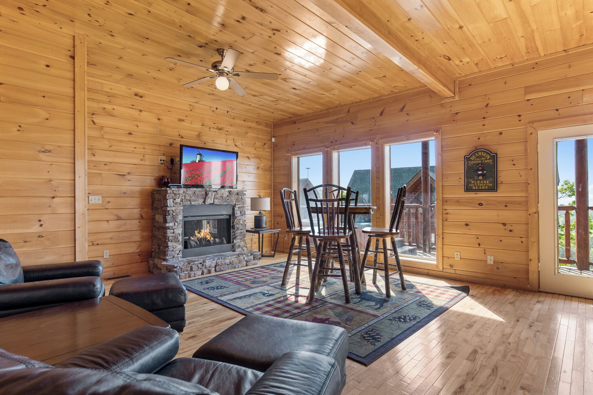 A cozy cabin interior with a stone fireplace, leather furniture, and a dining area.