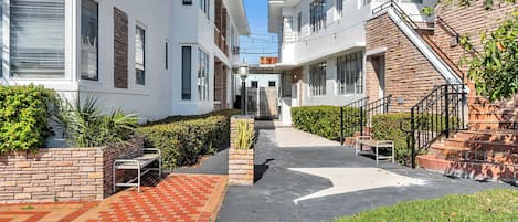 A courtyard with a brick pathway, benches, and a small garden area.