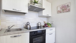 Una cocina moderna con armarios blancos, electrodomésticos de acero inoxidable y un salpicadero de azulejos.