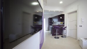 Una cucina moderna con mobili scuri, un'ampia finestra e un bancone con sgabelli viola.