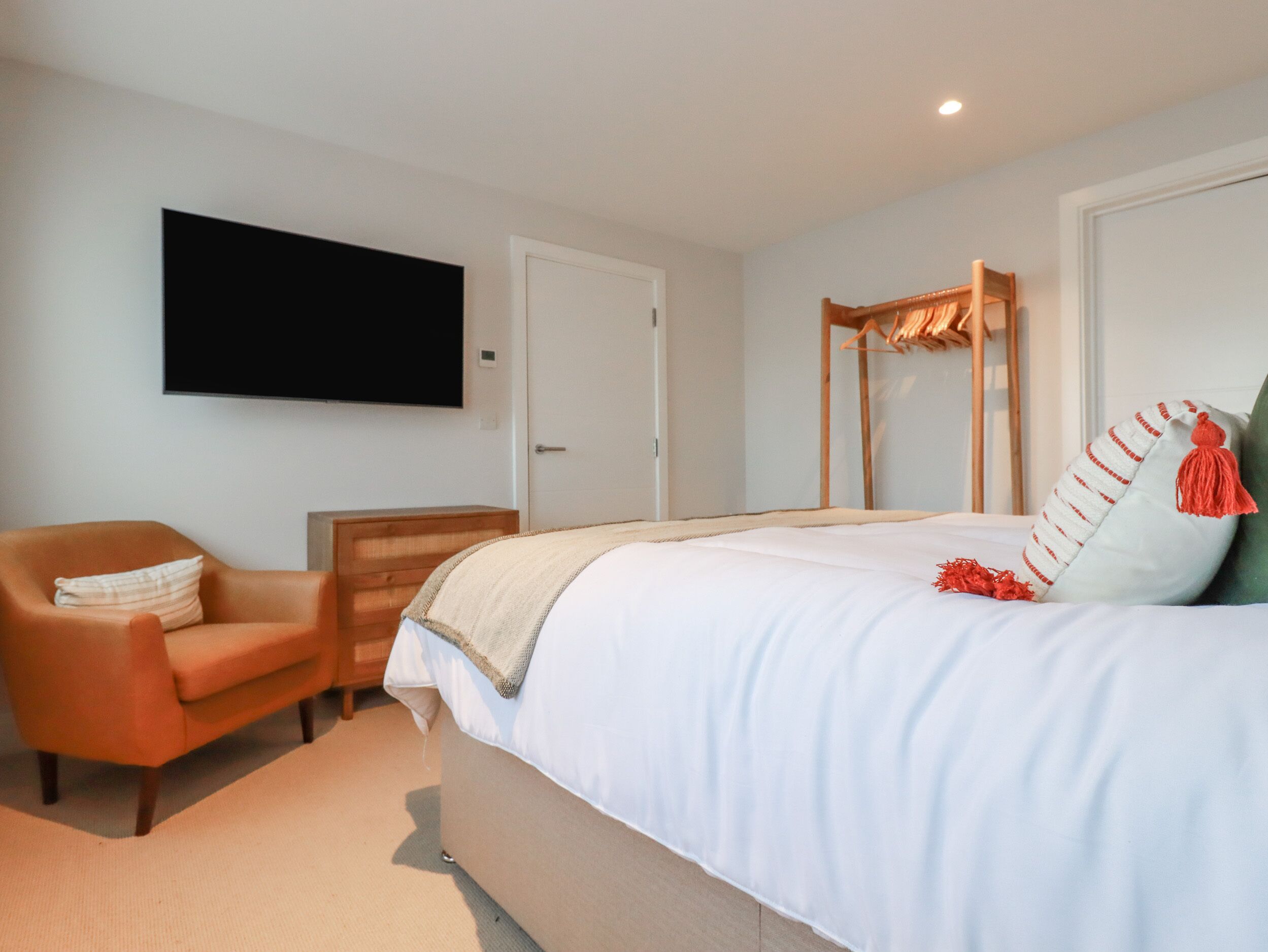 Une chambre à coucher comprenant un lit, une chaise, une commode, un téléviseur et une armoire.