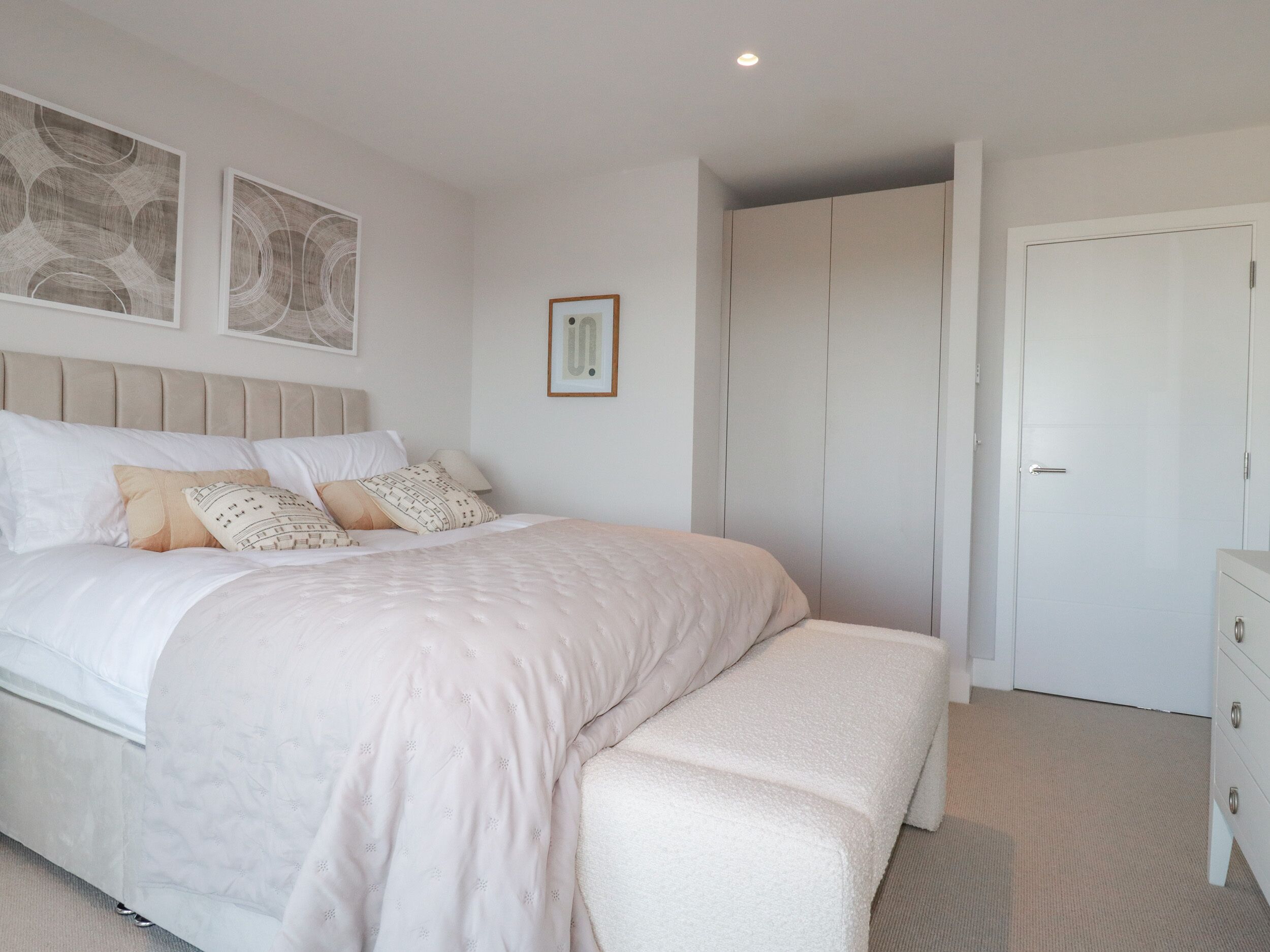 Une chambre à coucher avec un grand lit, une table de chevet, une armoire et un tableau encadré au mur.