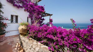 A building with vibrant purple bougainvillea flowers, a stone wall, and a view of the sea. - Villa San Montano in Massa Lubrense (Massa Lubrense)