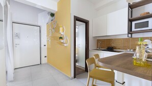 A modern kitchen with a central island, white cabinets, and a yellow accent wall. - Casa Cristina Yellow (Sorrento)