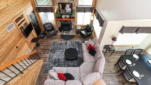 Un vaste espace de vie comprenant une cheminée, un canapé, une table à manger et un escalier.