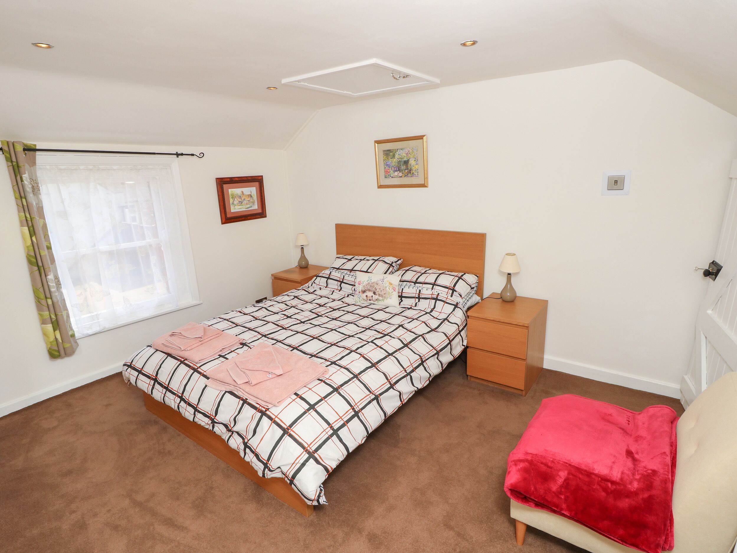 A bedroom with a bed, nightstands, a window with curtains, and a door.